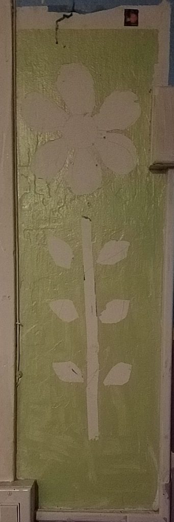 A green background with the outline of an unfinished flower, that has some pencil sketches and remains of blue tape in the white negative space the flower should occupy.